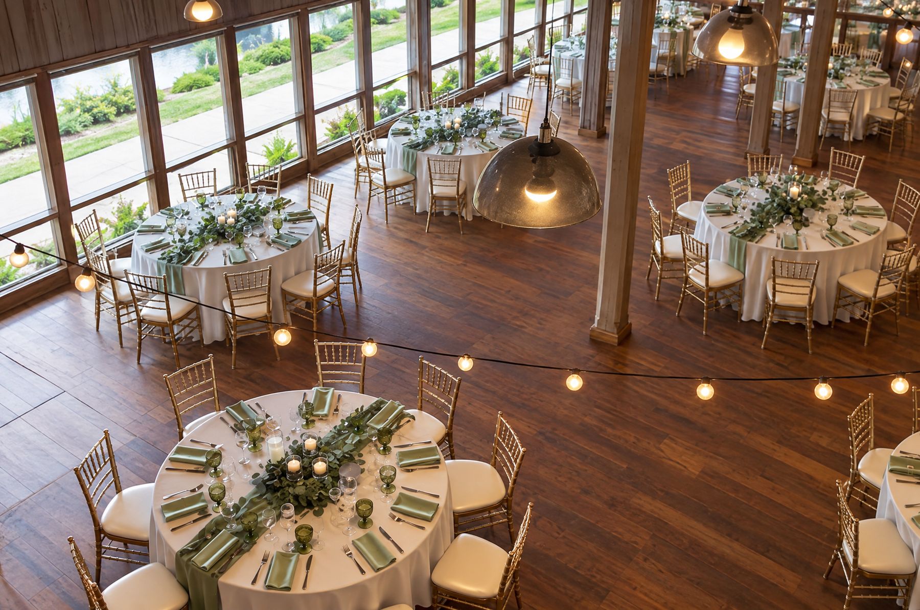 Event hall with round tables, greenery centrepieces and string lights